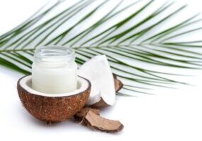 ripe coconut and organic coconut oil in glass jar with coconut leaf isolated on white